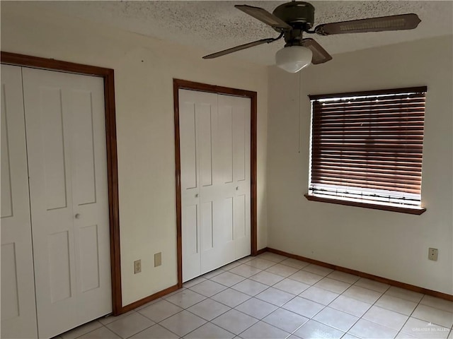 unfurnished bedroom with light tile patterned floors, a textured ceiling, a closet, and ceiling fan