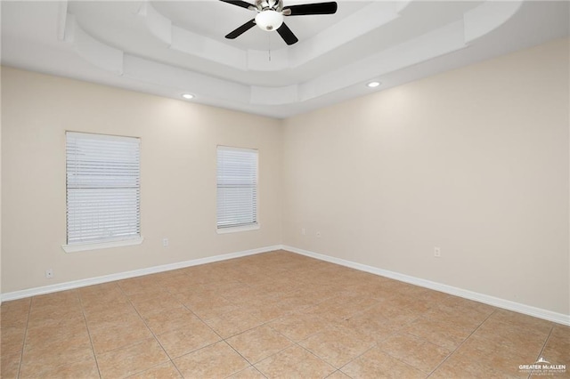 unfurnished room featuring ceiling fan, a tray ceiling, and light tile patterned floors