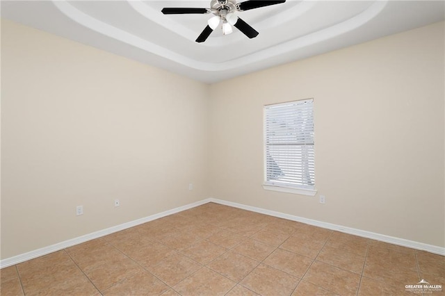 unfurnished room featuring a raised ceiling, ceiling fan, and light tile patterned flooring