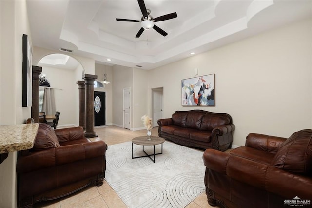 tiled living room featuring ceiling fan, a raised ceiling, and ornate columns