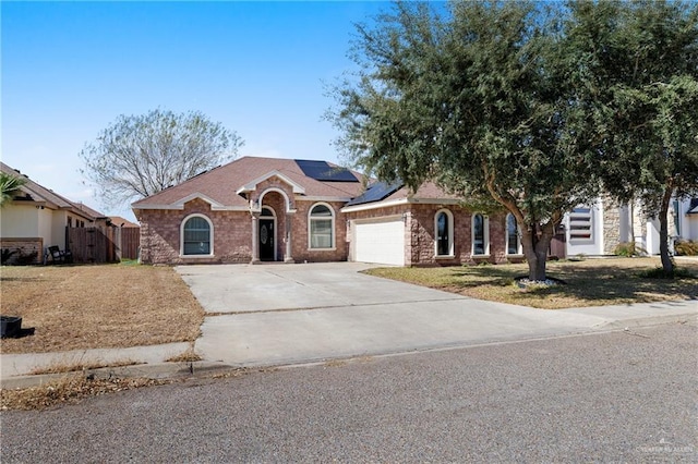 ranch-style home with a garage, a front yard, and solar panels