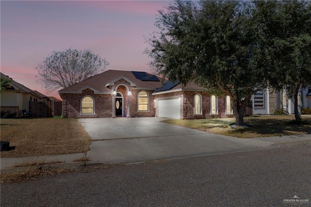 ranch-style house featuring a garage and solar panels