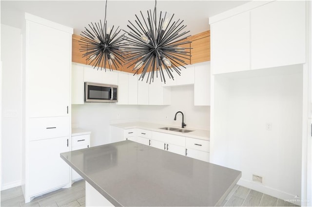 kitchen featuring white cabinetry, a kitchen island, sink, and light hardwood / wood-style flooring