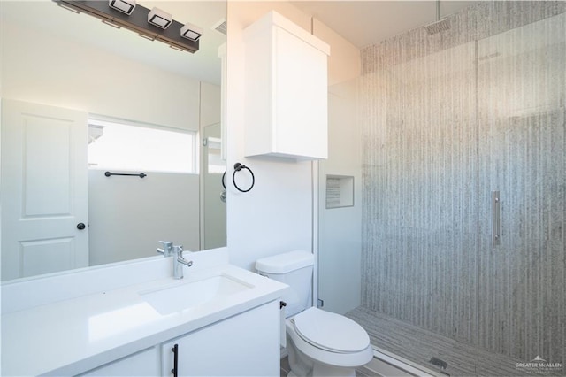 bathroom with vanity, a shower with door, and toilet