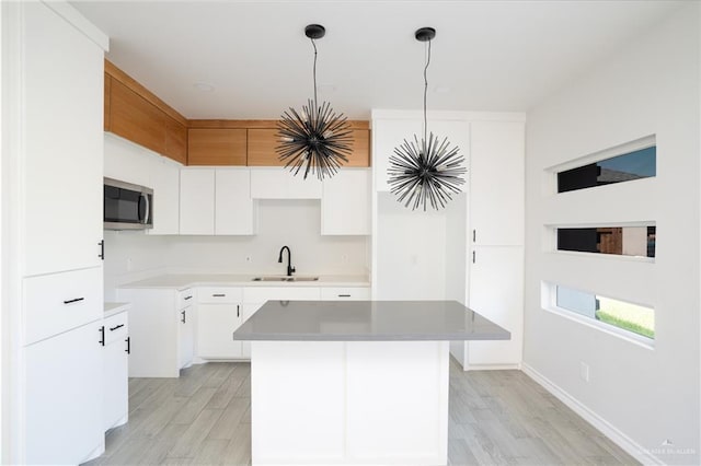 kitchen with white cabinetry, sink, pendant lighting, and a kitchen island