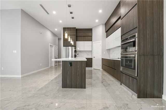 kitchen featuring pendant lighting, a center island with sink, sink, appliances with stainless steel finishes, and white cabinetry