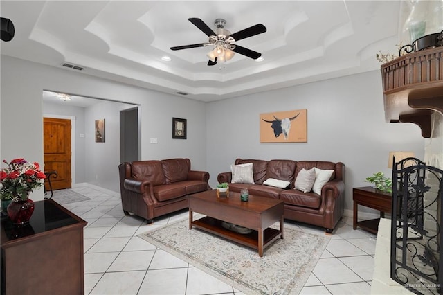 tiled living room featuring ceiling fan and a tray ceiling