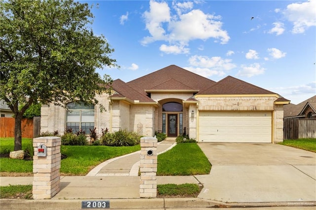 2003 N 44th Ln, Mcallen, TX 78501 - view of front facade with brick siding, concrete driveway, an attached garage, and roof with shingles