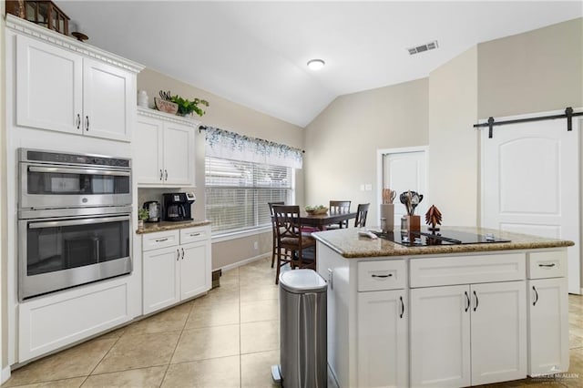 2003 N 44th Ln, Mcallen, TX 78501 - kitchen with double oven, black electric cooktop, vaulted ceiling, a barn door, and white cabinets