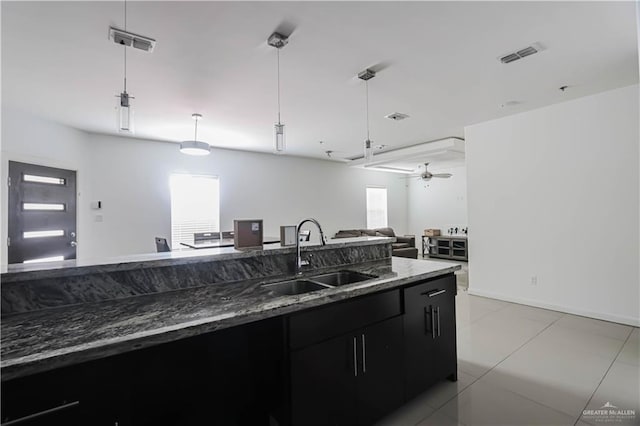 kitchen featuring dark cabinets, open floor plan, visible vents, and a sink