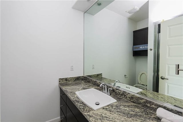 bathroom featuring toilet, vanity, and baseboards