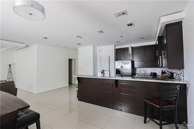 kitchen featuring decorative light fixtures, a breakfast bar area, visible vents, decorative backsplash, and appliances with stainless steel finishes