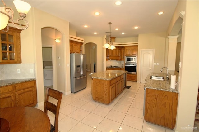 kitchen featuring tasteful backsplash, washer / clothes dryer, sink, a kitchen island with sink, and stainless steel appliances