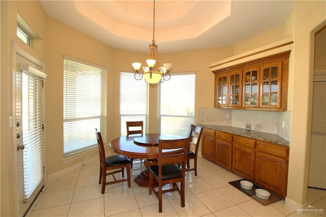 tiled dining room featuring a raised ceiling and an inviting chandelier