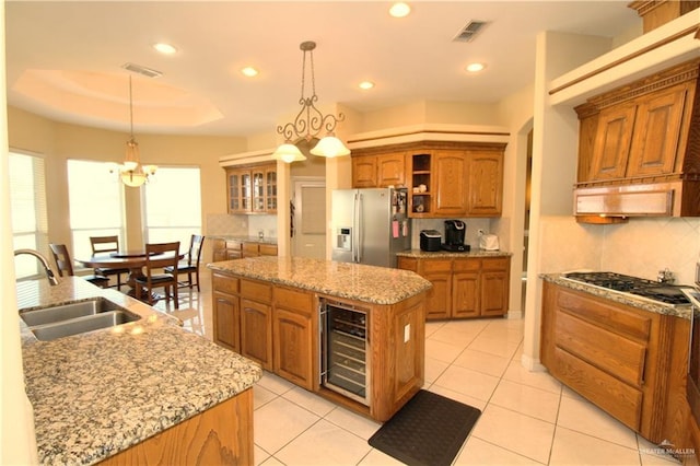 kitchen with sink, hanging light fixtures, stainless steel appliances, wine cooler, and a kitchen island