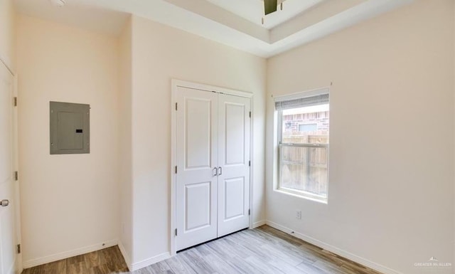 unfurnished bedroom with electric panel, a closet, and light hardwood / wood-style floors