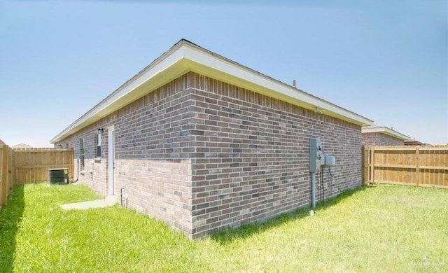 view of side of home with central AC and a lawn