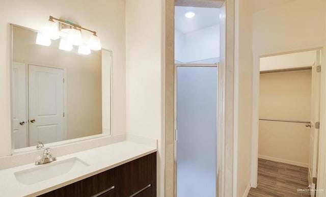 bathroom featuring hardwood / wood-style flooring, vanity, and walk in shower