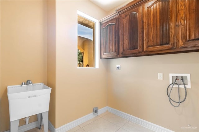 3210 Salvador Ave, Edinburg, TX 78539 - clothes washing area with electric dryer hookup, cabinet space, washer hookup, baseboards, and light tile patterned flooring