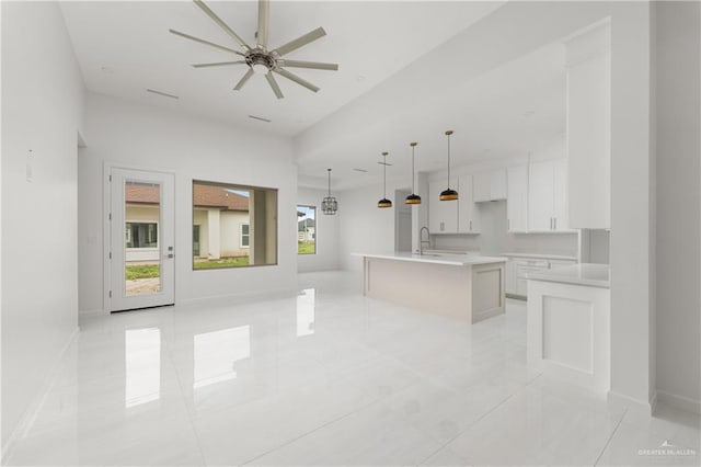 kitchen with ceiling fan, sink, decorative light fixtures, a kitchen island with sink, and white cabinets