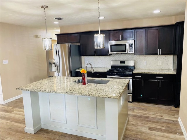 kitchen featuring hanging light fixtures, appliances with stainless steel finishes, sink, and a kitchen island with sink