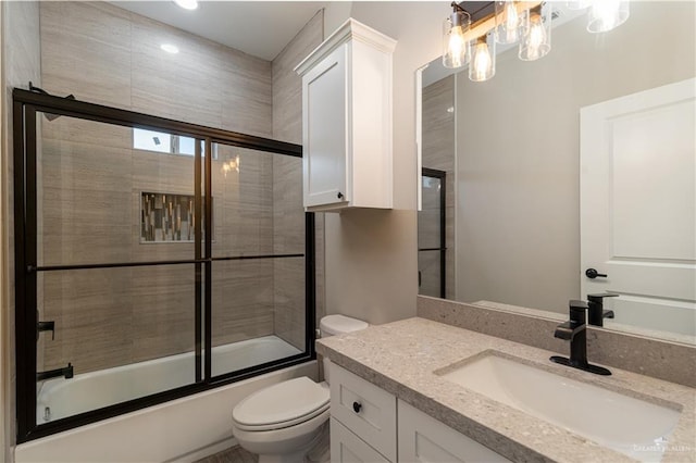 bathroom featuring toilet, enclosed tub / shower combo, and vanity