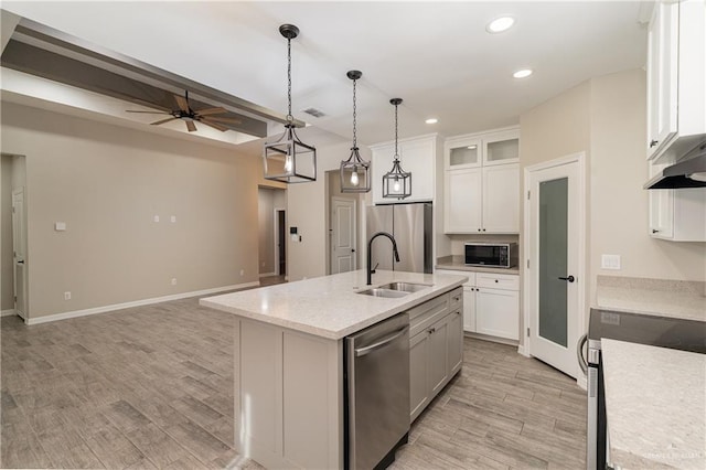 kitchen featuring appliances with stainless steel finishes, white cabinets, a sink, and light wood-style flooring