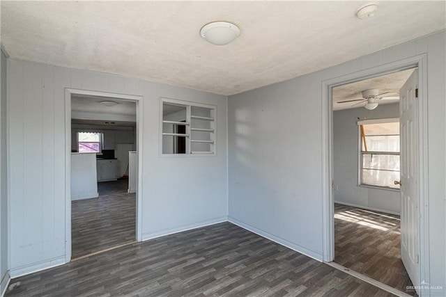 unfurnished room featuring built in shelves, ceiling fan, dark wood-type flooring, and a textured ceiling