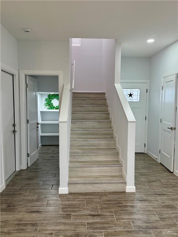 staircase featuring baseboards, wood finish floors, and recessed lighting