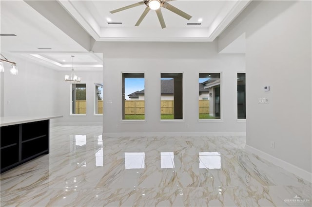 unfurnished room featuring ceiling fan with notable chandelier and a raised ceiling