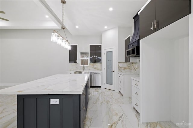 kitchen featuring decorative backsplash, appliances with stainless steel finishes, pendant lighting, white cabinets, and a center island