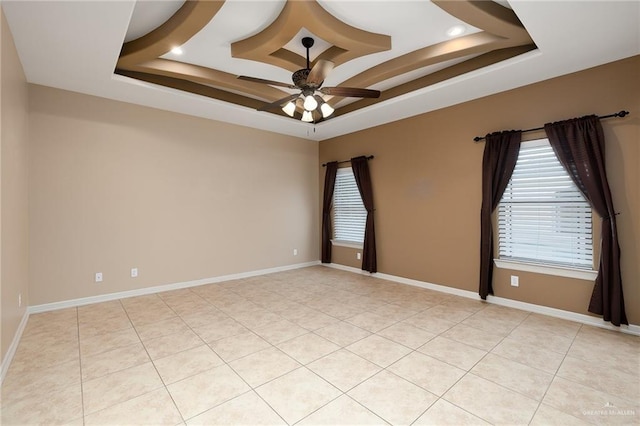 tiled empty room featuring ceiling fan and a tray ceiling