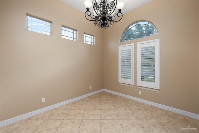 tiled spare room with a chandelier