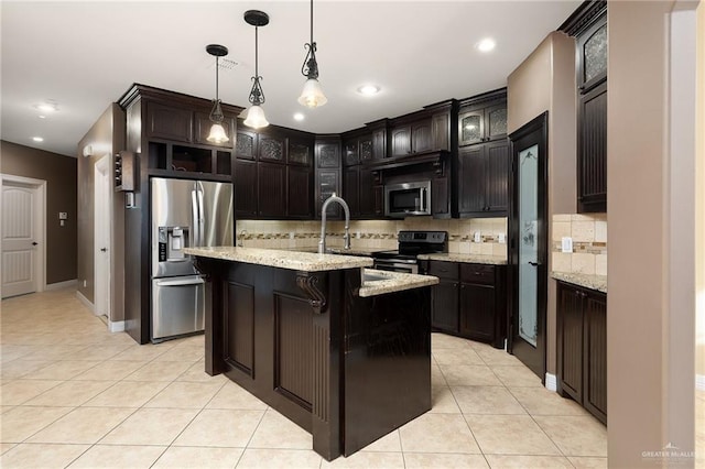 kitchen with decorative light fixtures, light tile patterned floors, stainless steel appliances, dark brown cabinets, and a center island with sink