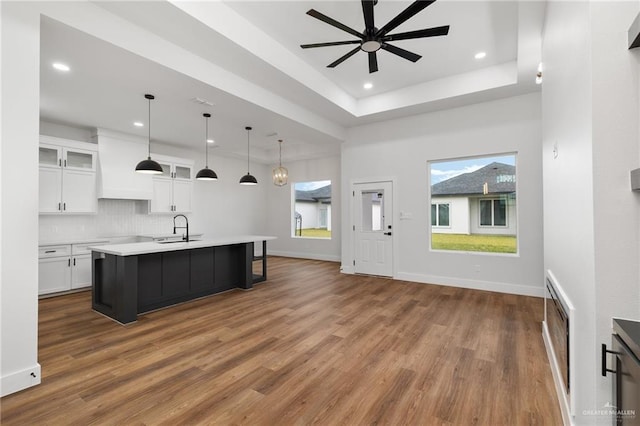 kitchen featuring a center island with sink, white cabinets, hanging light fixtures, and sink