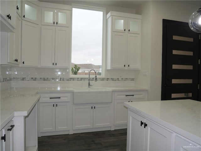 kitchen with light stone countertops, sink, backsplash, and white cabinets