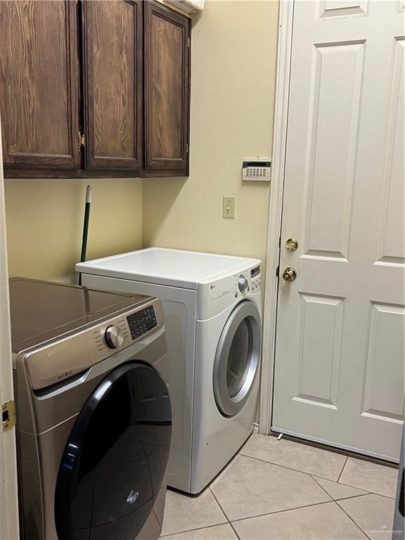 laundry area featuring washer and clothes dryer, cabinets, and light tile patterned floors