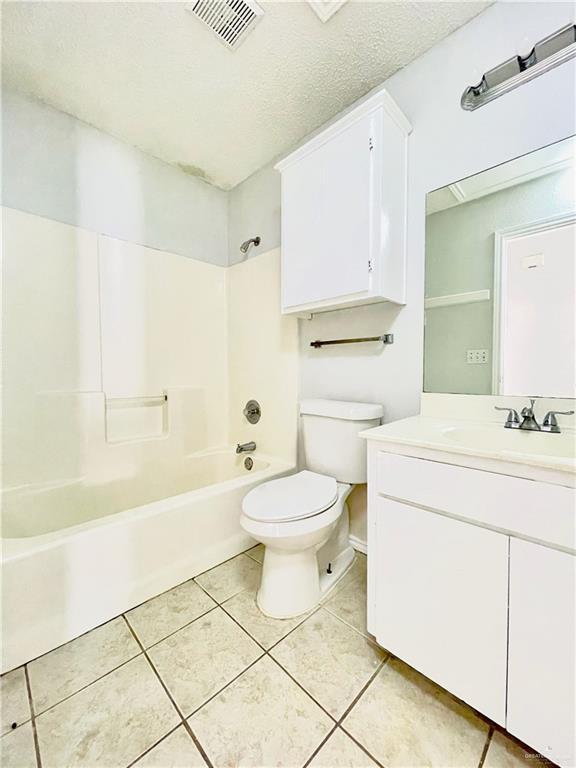 bathroom with toilet, vanity, visible vents, tub / shower combination, and tile patterned floors