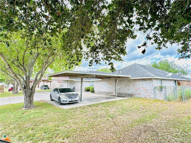 view of side of home with brick siding, a lawn, fence, and a detached carport