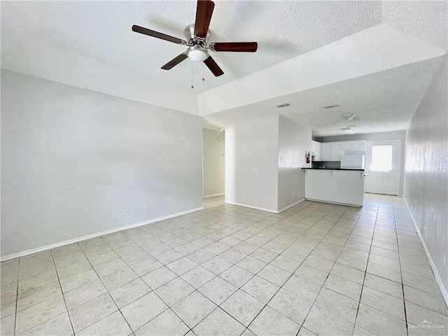 unfurnished living room with ceiling fan, a textured ceiling, baseboards, and light tile patterned floors