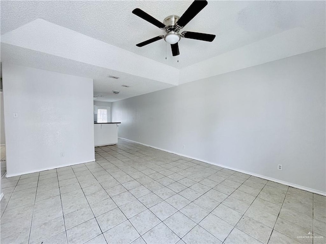 empty room featuring a textured ceiling, a ceiling fan, and baseboards