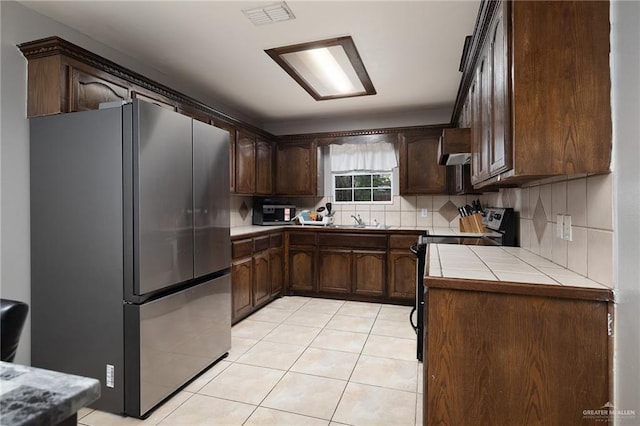 3608 Kingsborough Ave, Mcallen, TX 78504 - kitchen with stainless steel appliances, tile counters, light tile patterned floors, dark brown cabinets, and a sink