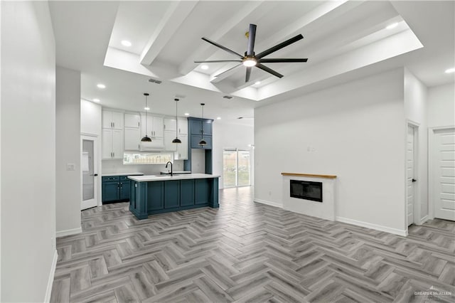 kitchen featuring white cabinetry, hanging light fixtures, a kitchen island with sink, and light parquet floors