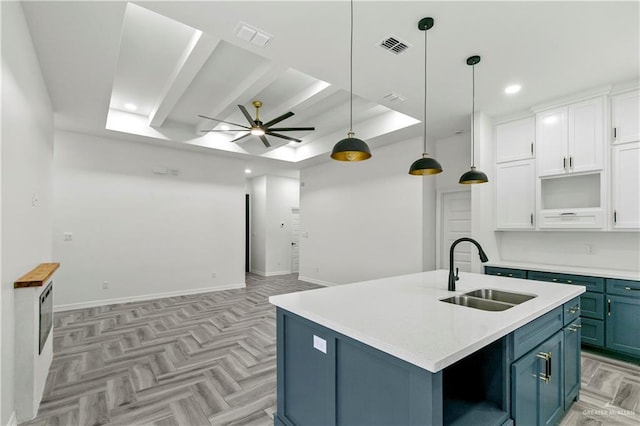 kitchen with white cabinetry, blue cabinetry, an island with sink, and sink