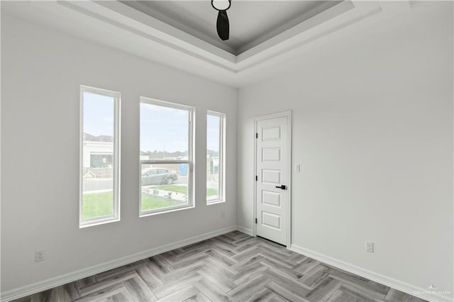 empty room featuring a raised ceiling and light parquet flooring