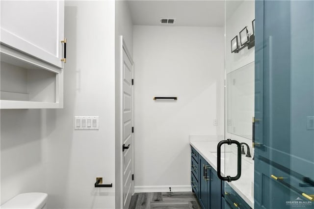 bathroom with hardwood / wood-style flooring, vanity, toilet, and a shower with door