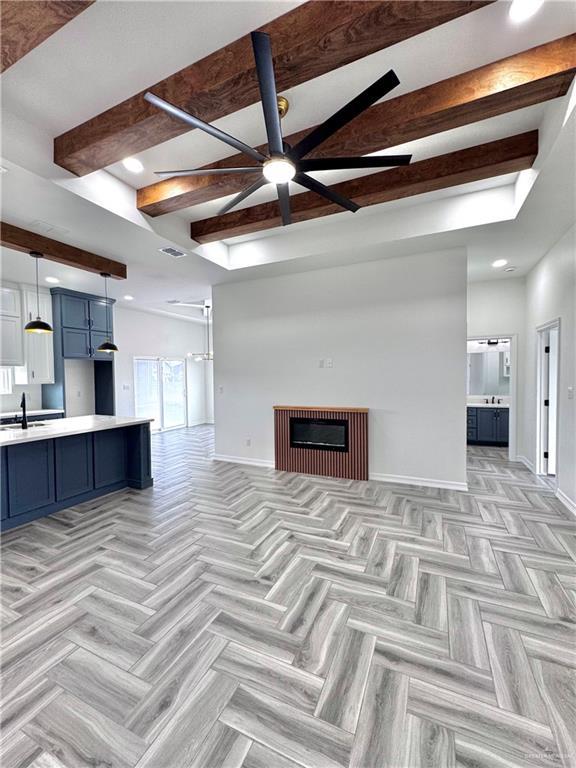 living room featuring ceiling fan, light parquet flooring, sink, and beamed ceiling