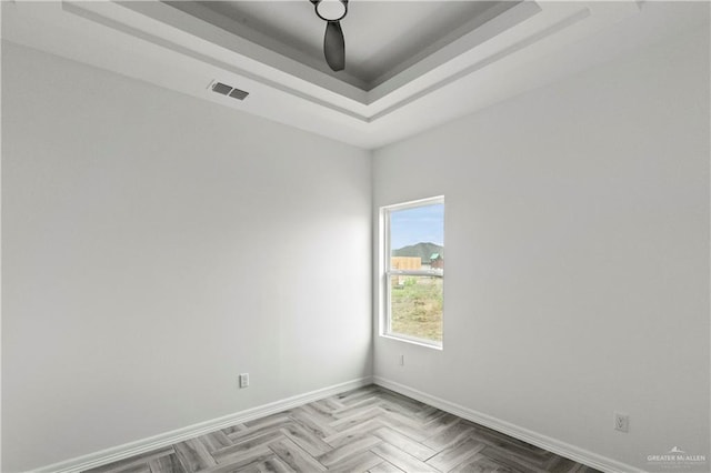 spare room featuring parquet flooring and a tray ceiling