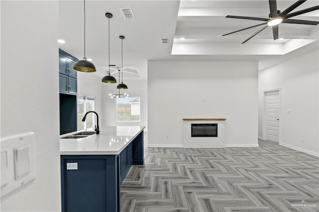 kitchen featuring blue cabinetry, pendant lighting, sink, and light parquet floors