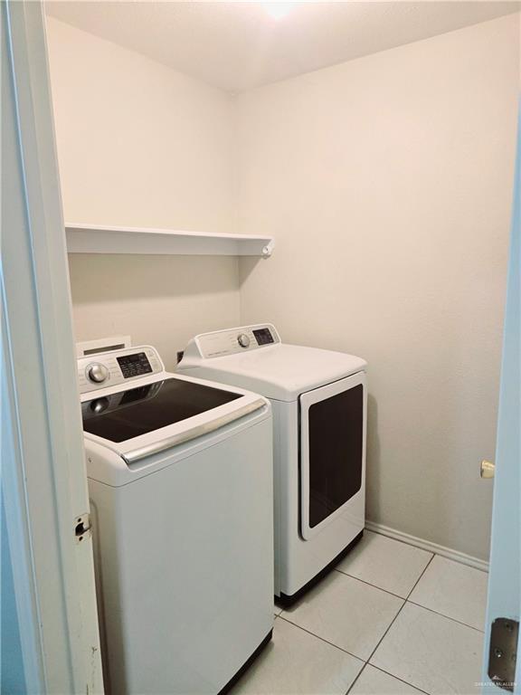 laundry room with washer and dryer and light tile patterned floors